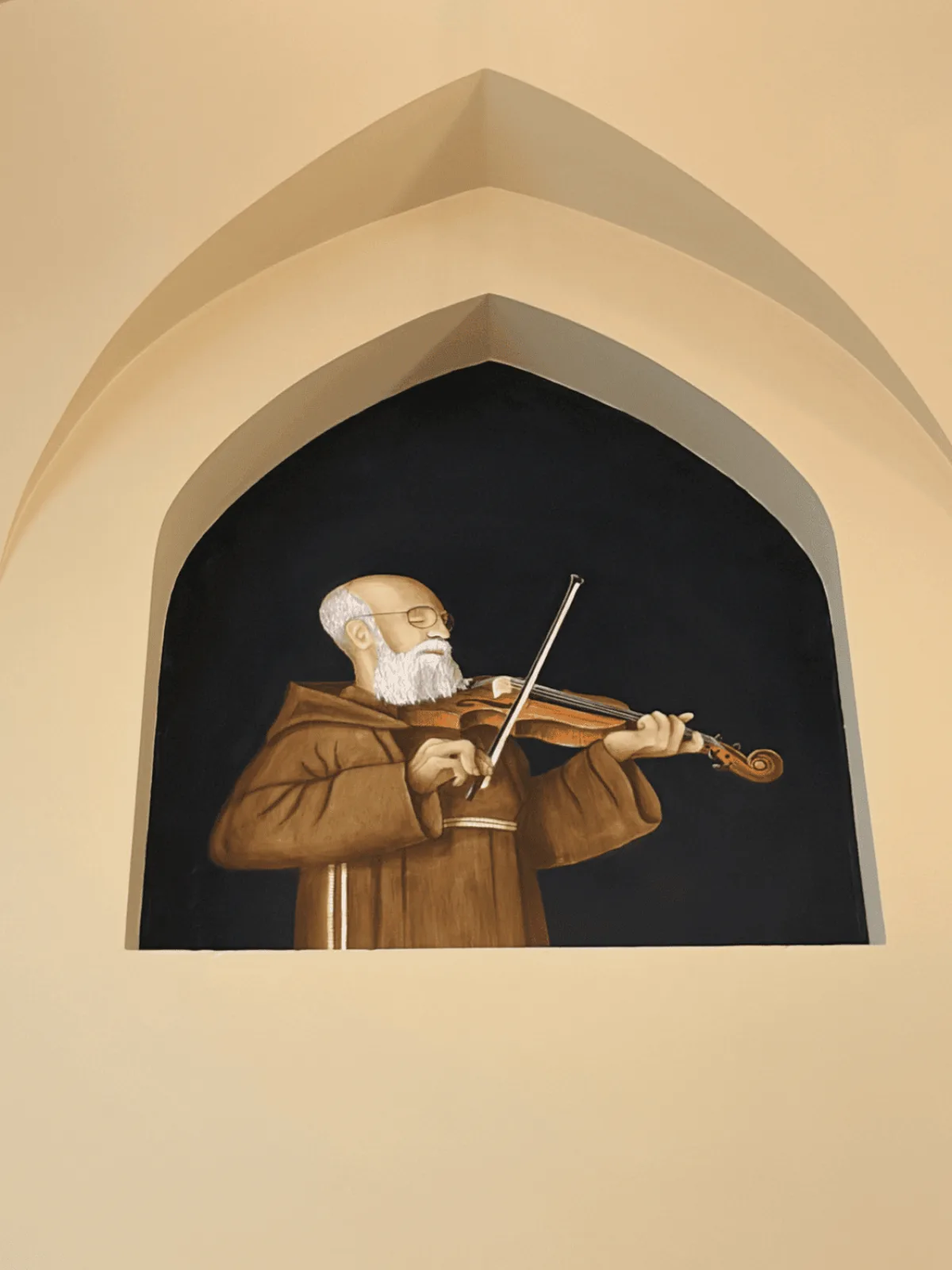 A statue of Solanus Casey playing his violin in a niche